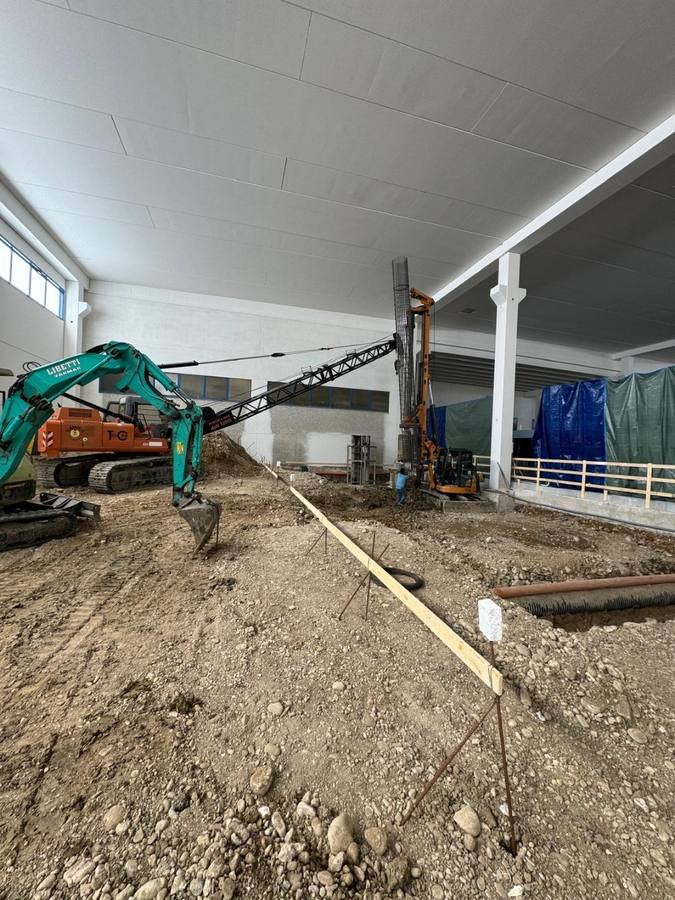 Escavatore e perforatrice in un capannone in costruzione