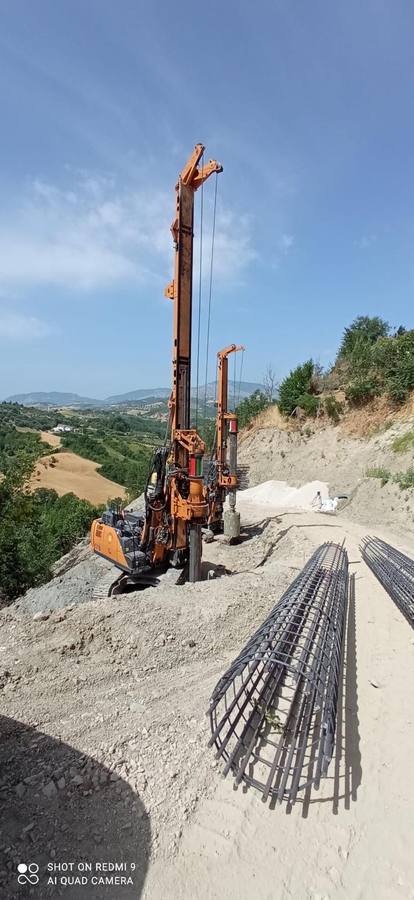 Panoramica di cantiere in collina con perforatrici e gabbie d'armatura