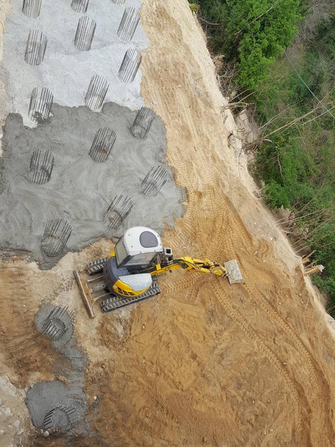 Mini-escavatore nella rifinitura del terreno attorno ai pali di fondazione